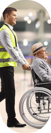 Une personne en fauteuil roulant qui se fait pousser par un employé de l'aéroport